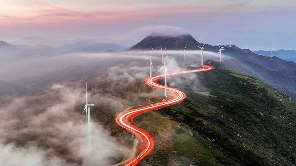 A red light weaving through wind turbines on hill tops.